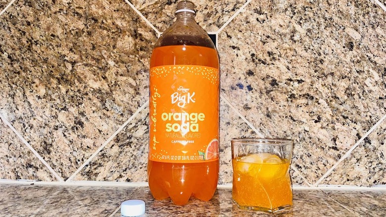 Two-liter and glass of Big K Orange Soda on marble counter