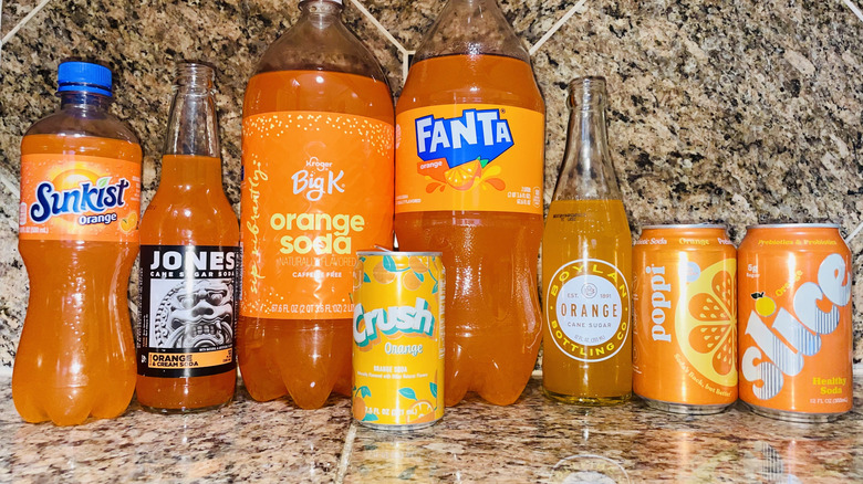 Collection of different orange sodas in bottles and cans