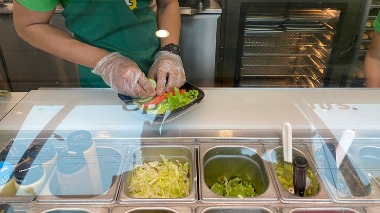 Subway sandwich artist making a sandwich.