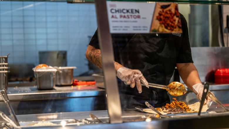 Chipotle employee preparing meal.