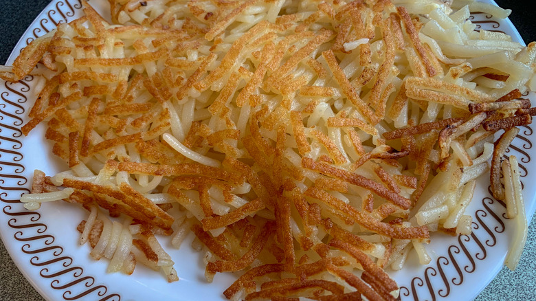 A crispy order of hash browns from Waffle House on a white plate