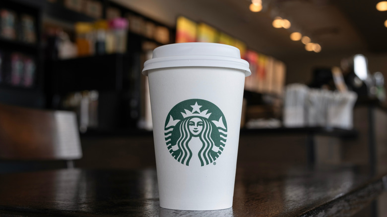 A cup of hot Starbucks coffee on a counter.