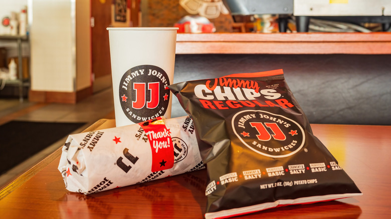 Jimmy John's sub, chips, and drink cup on a table inside a Jimmy John's restaurant