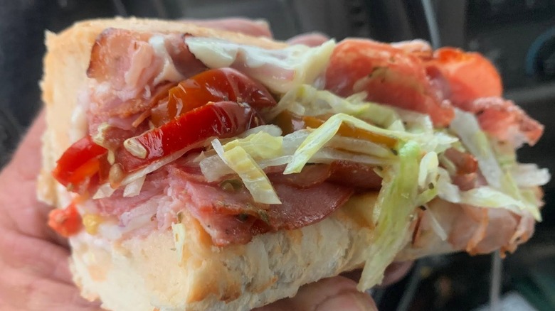 Person holding an Italian night club sandwich from Jimmy John's topped with hot peppers
