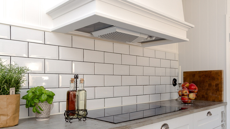 a white range hood hangs over a sleek kitchen countertop