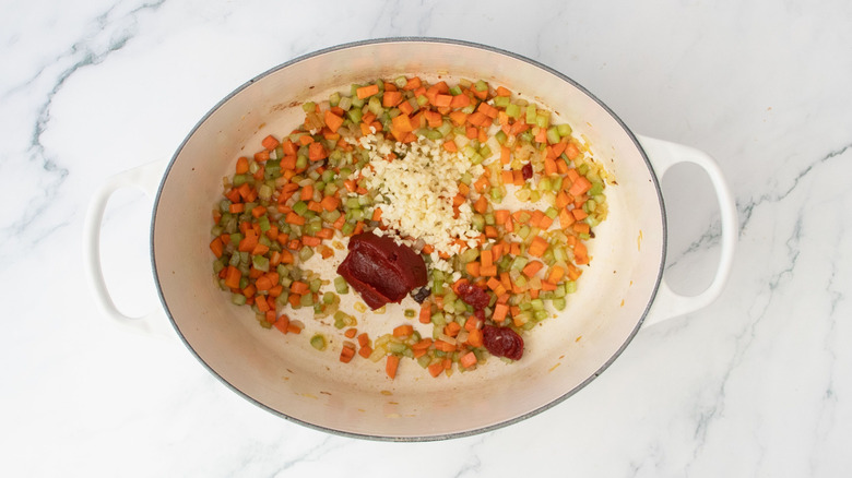 Mirepoix veggies with tomato paste and garlic in Dutch oven