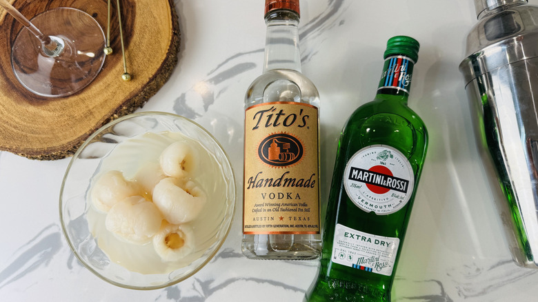 bowl of lychees and two liquor bottles on marble surface