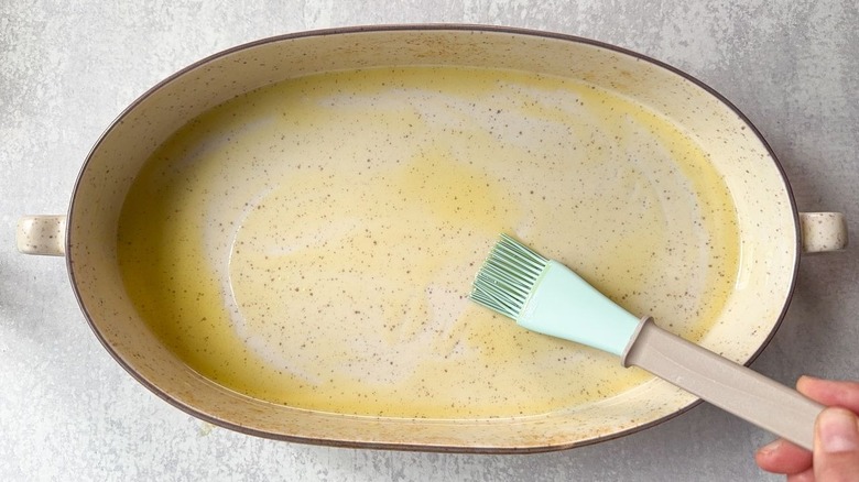 Brushing an oval baking dish with oil using a pastry brush