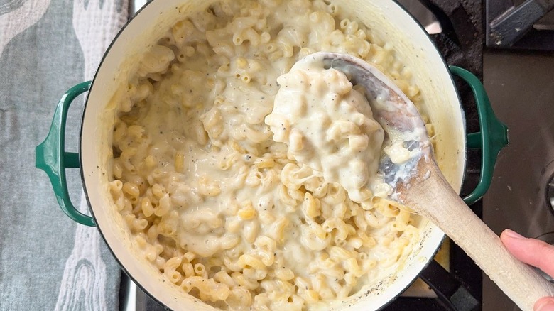 Stirring 3-ingredient mac & cheese with wooden spoon in large pot on stovetop