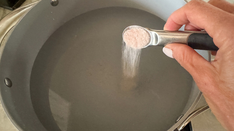 hand adding salt to pot