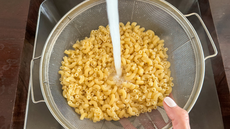 Macaroni in colander rinsing in sink