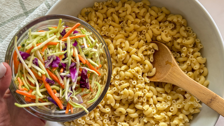 hand adding slaw to salad