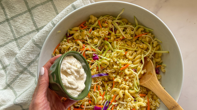 hand adding mayonnaise to bowl