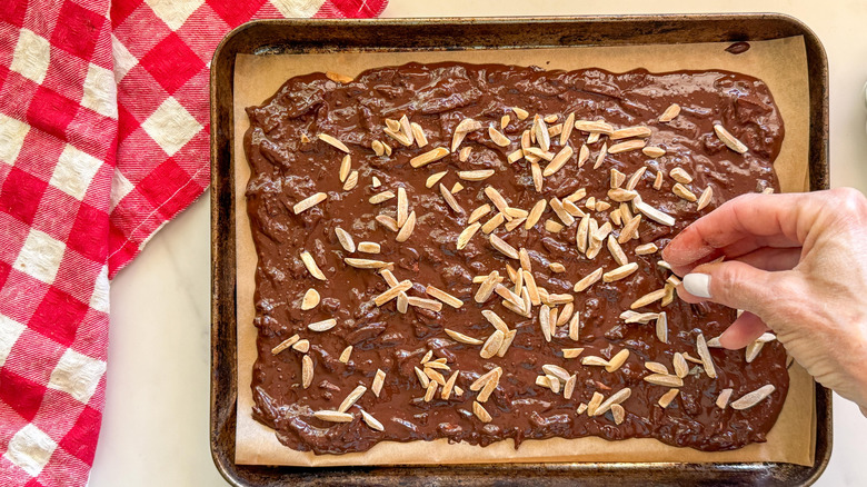 hand spreading almonds on chocolate