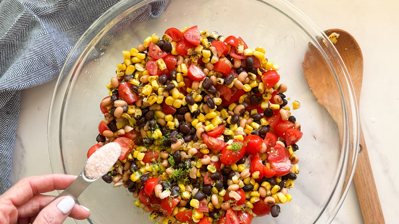 hand adding salt to bowl