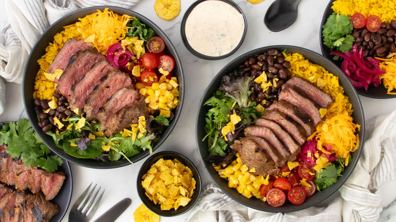 Steak taco bowls next to small bowl of crushed plantain chips and ranch