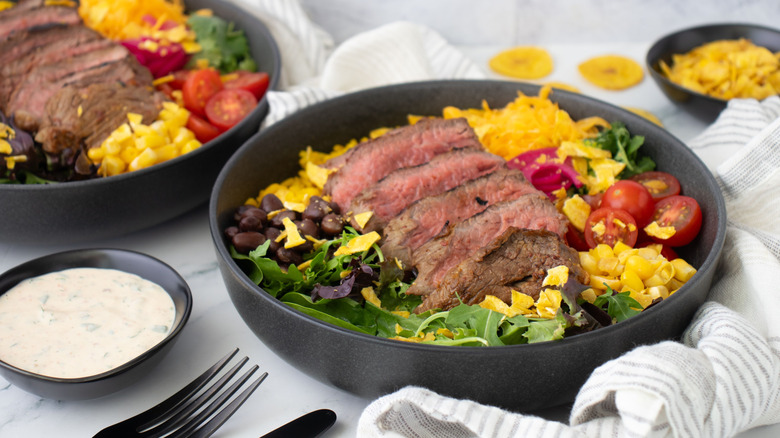 Steak taco salad bowl next to small bowl of ranch