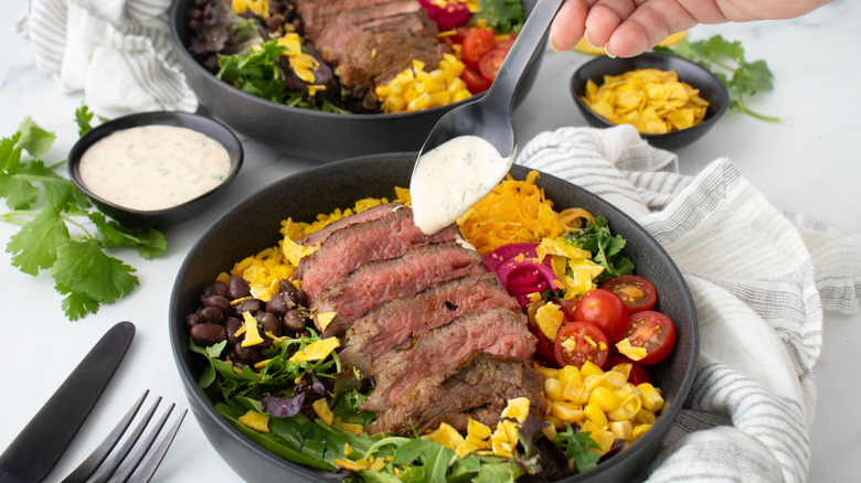Spoonful of ranch dressing going onto steak taco bowl