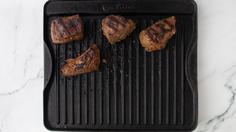 Grilled pieces of steak on grill pan