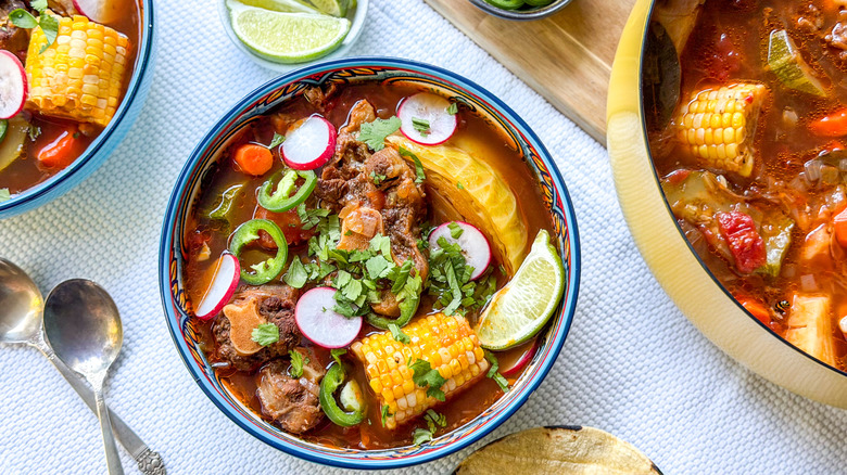 Caldo de Res in serving bowls with limes and tortillas