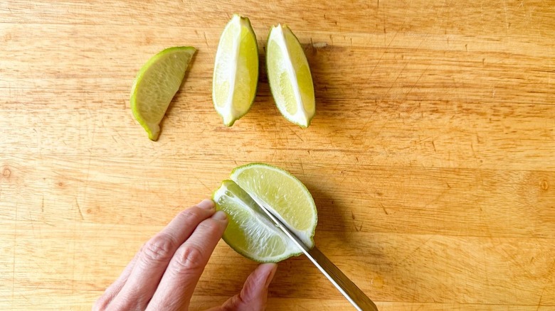 Cutting limes into wedges on cutting board