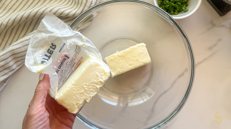 hand adding butter to bowl