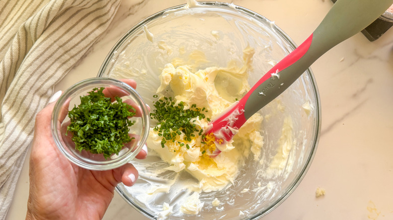 hand adding parsley to bowl