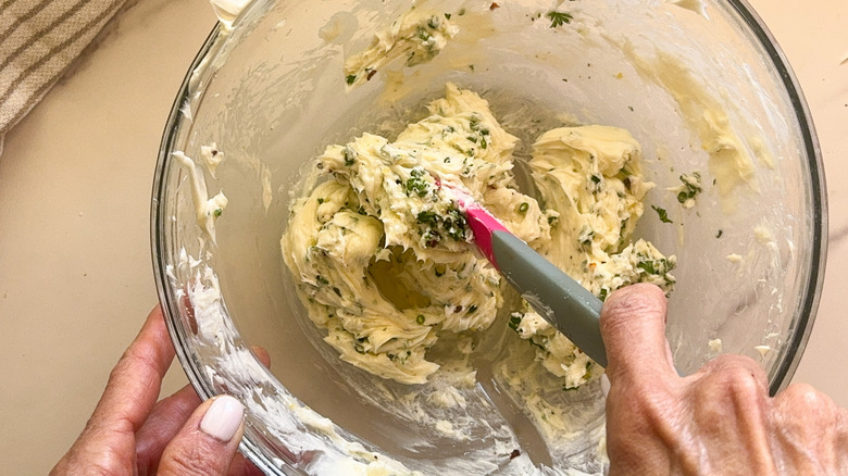 hand mixing butter with herbs
