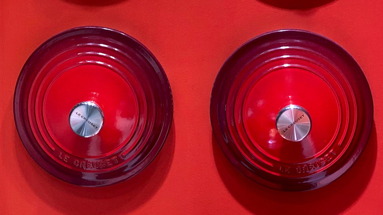 Cerise Le Creuset tops on red background.