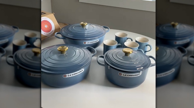 Le Creuset items in chambray color on white table.