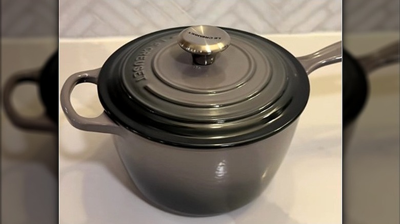 Oyster Le Creuset pan with lid sitting on countertop.