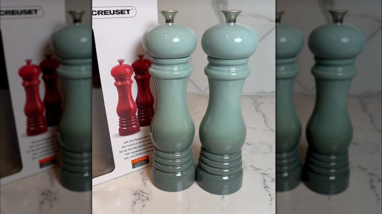 Sea salt La Creuset pepper grinders on counter in front of box.
