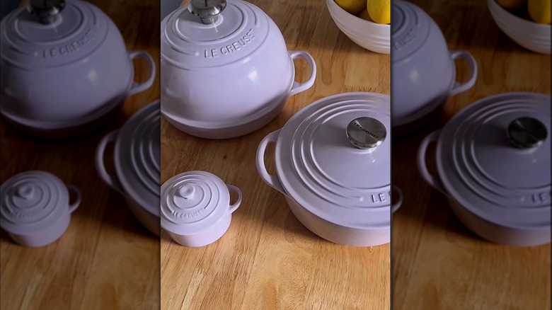 Several shallot Le Creuset products on wood table.