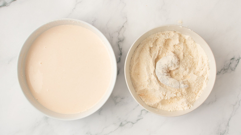 Bowl of buttermilk next to shrimp in bowl of flour