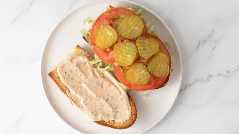 Open faced sandwich with remoulade, pickles, and tomatoes