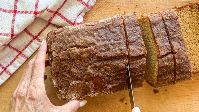 hand slicing bread on board