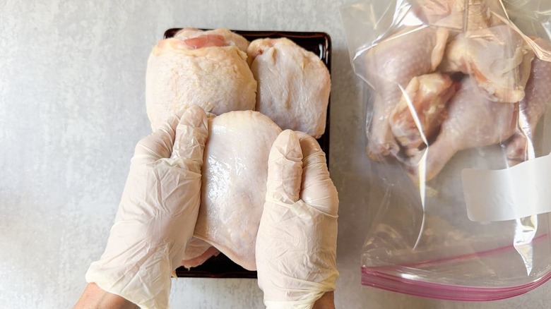 Rubbing skin-on chicken thighs with oil and ziplock bag with raw chicken pieces