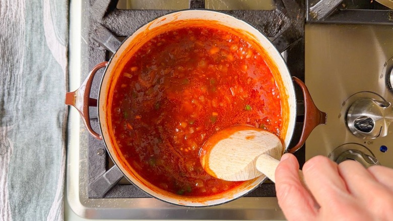 Stirring honey bourbon BBQ sauce with wooden spoon in pot on stovetop