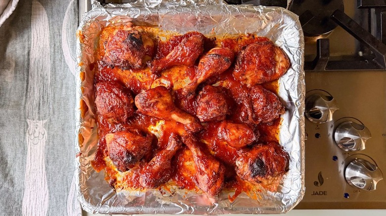 Honey bourbon BBQ chicken on foil-lined baking pan on stovetop