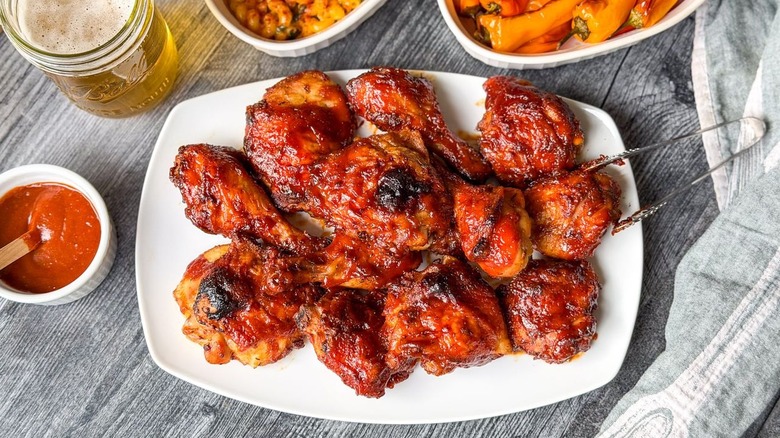 Honey bourbon BBQ chicken on serving platter with tongs and sides