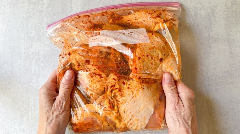Skin-on chicken legs and thighs in ziplock bag with spice rub