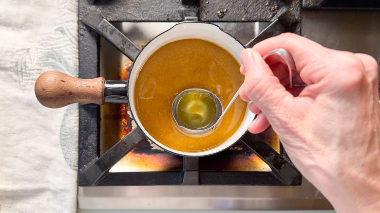 Skimming fat from ham pan drippings with ladle