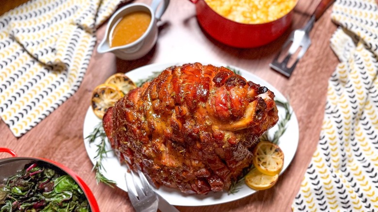Miso and maple-glazed ham on serving platter with gravy and greens