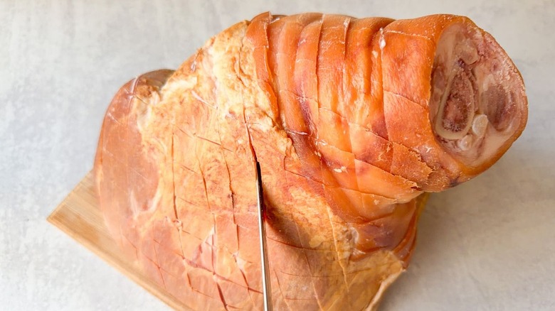 Scoring a whole ham with the tip of a knife