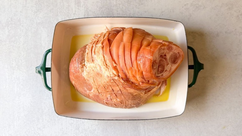 Scored bone-in ham in roasting pan