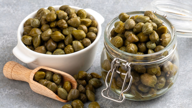 capers in glass jars with a wooden scoop