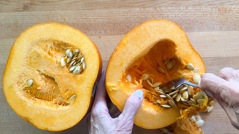hand scooping seeds out of pumpkin