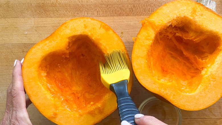 hand brushing pumpkin with olive oil