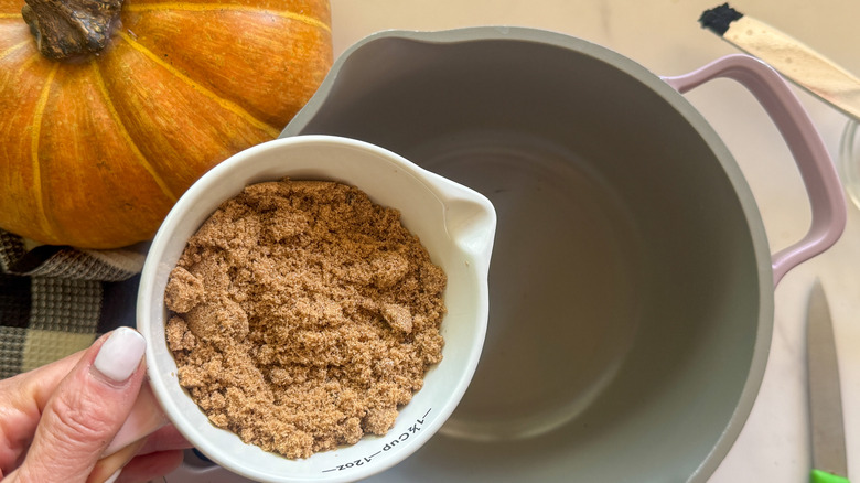 hand adding brown sugar to pot