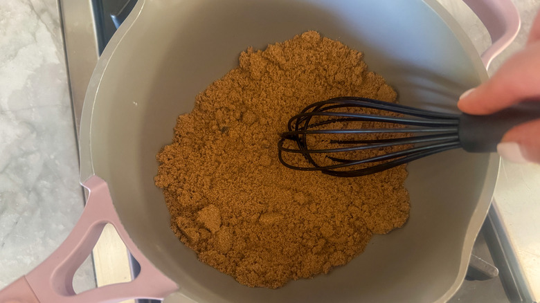 hand stirring sugar in pot